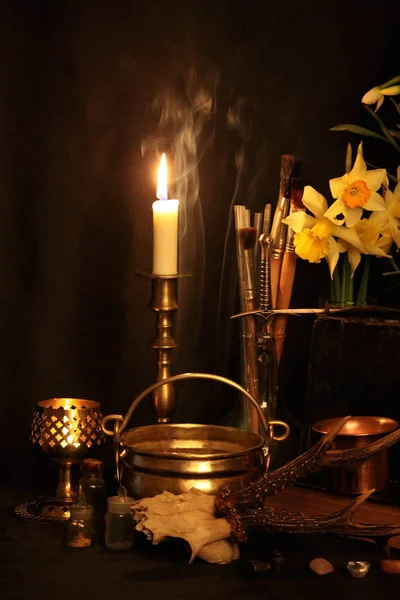 Kara büyü büyü. Wiccan büyüler ve otlar. Hala canlı: Eski yağ lambaları, antika kitap, bakır kase, ilaç şişeleri, lavanta, Pulsatilla pratensis bir antika arka plan üzerinde yanan bir muma gül tomurcukları kurutulmuş. Wicca arka plan.
