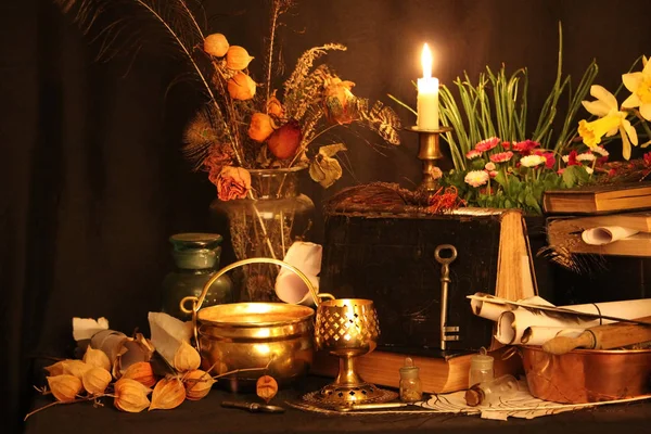 Black Magic Spells. Wiccan spells and herbs. Still Live: Old oil lamps, antique books, dried rose buds, a burning candle in a copper bowl, medicine bottles, lavender, Pulsatilla pratensis on an antique background. Wicca background.