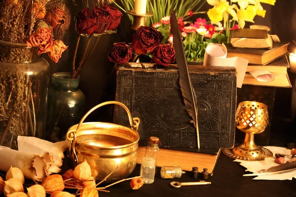 Black Magic Spells. Wiccan spells and herbs. Still Live: Old oil lamps, antique books, dried rose buds, a burning candle in a copper bowl, medicine bottles, lavender, Pulsatilla pratensis on an antique background. Wicca background.