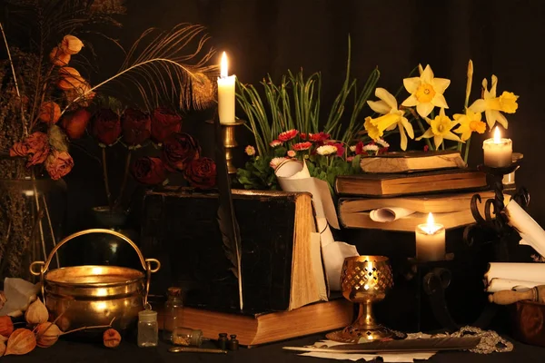 Kara büyü büyü. Wiccan büyüler ve otlar. Hala canlı: Eski yağ lambaları, antika kitap, bakır kase, ilaç şişeleri, lavanta, Pulsatilla pratensis bir antika arka plan üzerinde yanan bir muma gül tomurcukları kurutulmuş. Wicca arka plan.