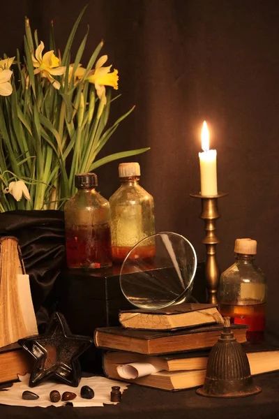 Kara büyü büyü. Wiccan büyüler ve otlar. Hala canlı: Eski yağ lambaları, antika kitap, bakır kase, ilaç şişeleri, lavanta, Pulsatilla pratensis bir antika arka plan üzerinde yanan bir muma gül tomurcukları kurutulmuş. Wicca arka plan.