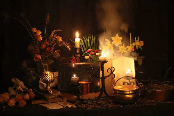 Kara büyü büyü. Wiccan büyüler ve otlar. Hala canlı: Eski yağ lambaları, antika kitap, bakır kase, ilaç şişeleri, lavanta, Pulsatilla pratensis bir antika arka plan üzerinde yanan bir muma gül tomurcukları kurutulmuş. Wicca arka plan.