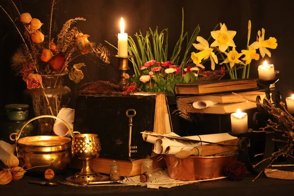 Kara büyü büyü. Wiccan büyüler ve otlar. Hala canlı: Eski yağ lambaları, antika kitap, bakır kase, ilaç şişeleri, lavanta, Pulsatilla pratensis bir antika arka plan üzerinde yanan bir muma gül tomurcukları kurutulmuş. Wicca arka plan.