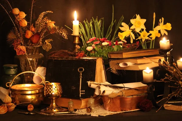 Black Magic Spells. Wiccan spells and herbs. Still Live: Old oil lamps, antique books, dried rose buds, a burning candle in a copper bowl, medicine bottles, lavender, Pulsatilla pratensis on an antique background. Wicca background.