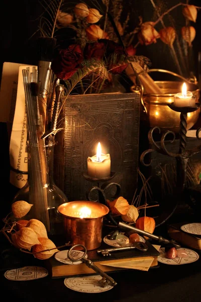 Kara büyü büyü. Wiccan büyüler ve otlar. Hala canlı: Eski yağ lambaları, antika kitap, bakır kase, ilaç şişeleri, lavanta, Pulsatilla pratensis bir antika arka plan üzerinde yanan bir muma gül tomurcukları kurutulmuş. Wicca arka plan.