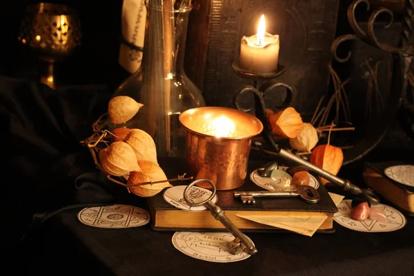 Kara büyü büyü. Wiccan büyüler ve otlar. Hala canlı: Eski yağ lambaları, antika kitap, bakır kase, ilaç şişeleri, lavanta, Pulsatilla pratensis bir antika arka plan üzerinde yanan bir muma gül tomurcukları kurutulmuş. Wicca arka plan.