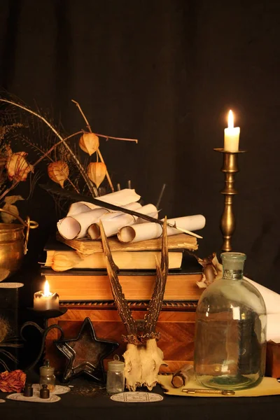 Kara büyü büyü. Wiccan büyüler ve otlar. Hala canlı: Eski yağ lambaları, antika kitap, bakır kase, ilaç şişeleri, lavanta, Pulsatilla pratensis bir antika arka plan üzerinde yanan bir muma gül tomurcukları kurutulmuş. Wicca arka plan.