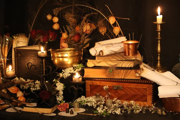 Kara büyü büyü. Wiccan büyüler ve otlar. Hala canlı: Eski yağ lambaları, antika kitap, bakır kase, ilaç şişeleri, lavanta, Pulsatilla pratensis bir antika arka plan üzerinde yanan bir muma gül tomurcukları kurutulmuş. Wicca arka plan.