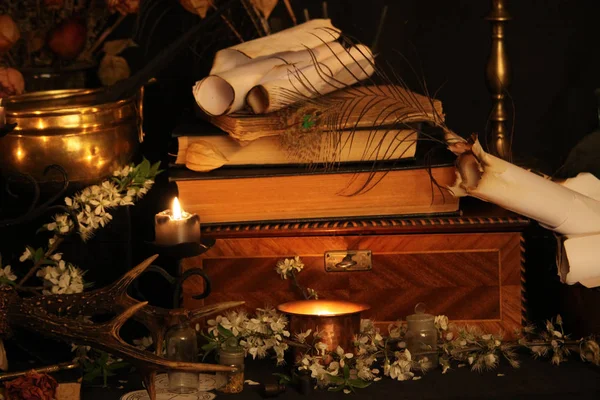 Kara büyü büyü. Wiccan büyüler ve otlar. Hala canlı: Eski yağ lambaları, antika kitap, bakır kase, ilaç şişeleri, lavanta, Pulsatilla pratensis bir antika arka plan üzerinde yanan bir muma gül tomurcukları kurutulmuş. Wicca arka plan.