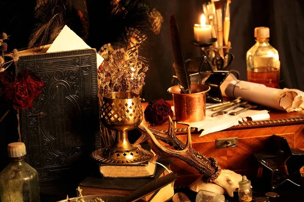 Kara büyü büyü. Wiccan büyüler ve otlar. Hala canlı: Eski yağ lambaları, antika kitap, bakır kase, ilaç şişeleri, lavanta, Pulsatilla pratensis bir antika arka plan üzerinde yanan bir muma gül tomurcukları kurutulmuş. Wicca arka plan.