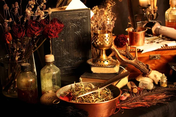 Black Magic Spells. Wiccan spells and herbs. Still Live: Old oil lamps, antique books, dried rose buds, a burning candle in a copper bowl, medicine bottles, lavender, Pulsatilla pratensis on an antique background. Wicca background.