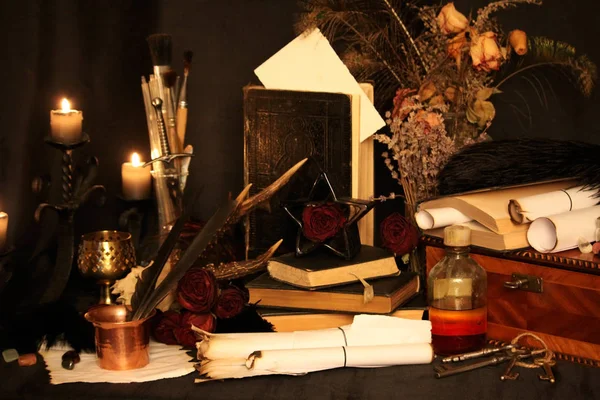 Kara büyü büyü. Wiccan büyüler ve otlar. Hala canlı: Eski yağ lambaları, antika kitap, bakır kase, ilaç şişeleri, lavanta, Pulsatilla pratensis bir antika arka plan üzerinde yanan bir muma gül tomurcukları kurutulmuş. Wicca arka plan.