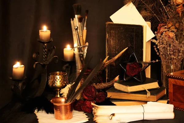 Black Magic Spells. Wiccan spells and herbs. Still Live: Old oil lamps, antique books, dried rose buds, a burning candle in a copper bowl, medicine bottles, lavender, Pulsatilla pratensis on an antique background. Wicca background.