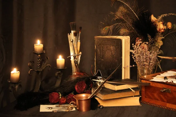 Kara büyü büyü. Wiccan büyüler ve otlar. Hala canlı: Eski yağ lambaları, antika kitap, bakır kase, ilaç şişeleri, lavanta, Pulsatilla pratensis bir antika arka plan üzerinde yanan bir muma gül tomurcukları kurutulmuş. Wicca arka plan.