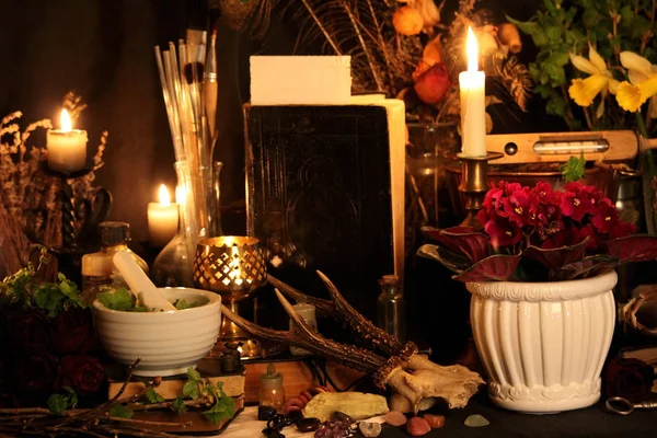 Kara büyü büyü. Wiccan büyüler ve otlar. Hala canlı: Eski yağ lambaları, antika kitap, bakır kase, ilaç şişeleri, lavanta, Pulsatilla pratensis bir antika arka plan üzerinde yanan bir muma gül tomurcukları kurutulmuş. Wicca arka plan.