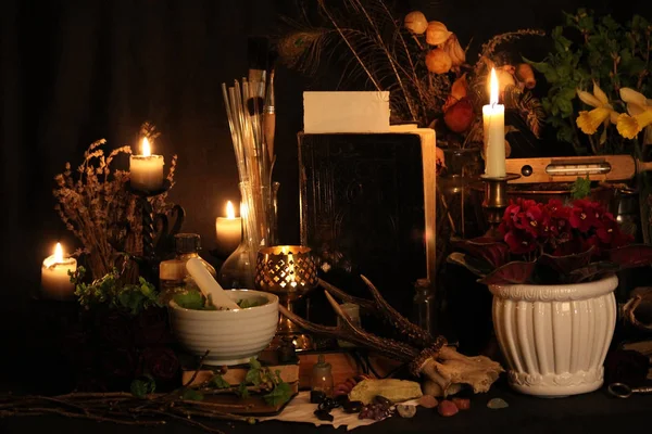 Kara büyü büyü. Wiccan büyüler ve otlar. Hala canlı: Eski yağ lambaları, antika kitap, bakır kase, ilaç şişeleri, lavanta, Pulsatilla pratensis bir antika arka plan üzerinde yanan bir muma gül tomurcukları kurutulmuş. Wicca arka plan.