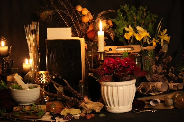 Black Magic Spells. Wiccan spells and herbs. Still Live: Old oil lamps, antique books, dried rose buds, a burning candle in a copper bowl, medicine bottles, lavender, Pulsatilla pratensis on an antique background. Wicca background.