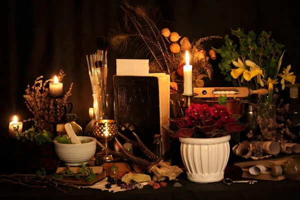 Kara büyü büyü. Wiccan büyüler ve otlar. Hala canlı: Eski yağ lambaları, antika kitap, bakır kase, ilaç şişeleri, lavanta, Pulsatilla pratensis bir antika arka plan üzerinde yanan bir muma gül tomurcukları kurutulmuş. Wicca arka plan.