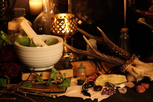 Kara büyü büyü. Wiccan büyüler ve otlar. Hala canlı: Eski yağ lambaları, antika kitap, bakır kase, ilaç şişeleri, lavanta, Pulsatilla pratensis bir antika arka plan üzerinde yanan bir muma gül tomurcukları kurutulmuş. Wicca arka plan.