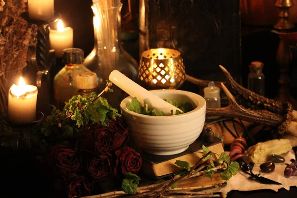 Black Magic Spells. Wiccan spells and herbs. Still Live: Old oil lamps, antique books, dried rose buds, a burning candle in a copper bowl, medicine bottles, lavender, Pulsatilla pratensis on an antique background. Wicca background.
