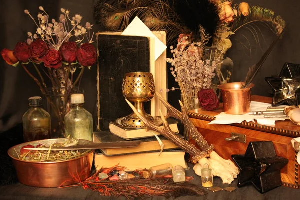 Kara büyü büyü. Wiccan büyüler ve otlar. Hala canlı: Eski yağ lambaları, antika kitap, bakır kase, ilaç şişeleri, lavanta, Pulsatilla pratensis bir antika arka plan üzerinde yanan bir muma gül tomurcukları kurutulmuş. Wicca arka plan.