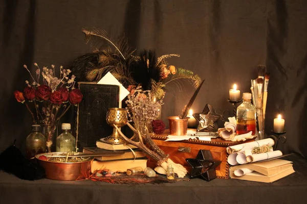 Black Magic Spells. Wiccan spells and herbs. Still Live: Old oil lamps, antique books, dried rose buds, a burning candle in a copper bowl, medicine bottles, lavender, Pulsatilla pratensis on an antique background. Wicca background.