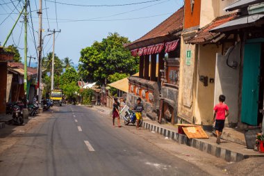 BALI, INDONESIA - 01 Aralık 2019: Geleneksel Bali Kabile Köyü. Endonezya 'da Bali caddesi boyunca arabalar ve motosikletler sürüyor