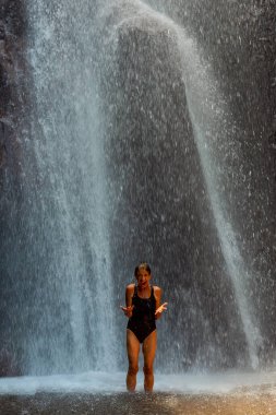 BALI, INDONESIA - 01 Aralık 2019: şelale altında çığlık atan kadın ruhsal temizlik seansı. Bali, Endonezya