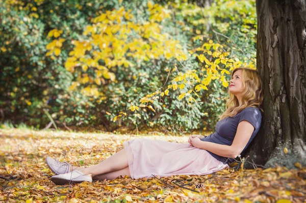 秋天的城市公园里 一位年轻的女士坐在树下 白日做梦的心情 — 图库照片