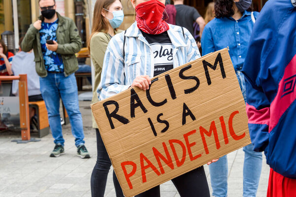 Wroclaw, Poland, 06.06.2020 - Young people hold a poster with words "Racism is a pandemic" on polish peaceful protest against racism and hatred in Wroclaw city.