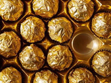 Üstten altın folyo görünümlü çikolata topları. Şeker kutusunda boş bir yer var.