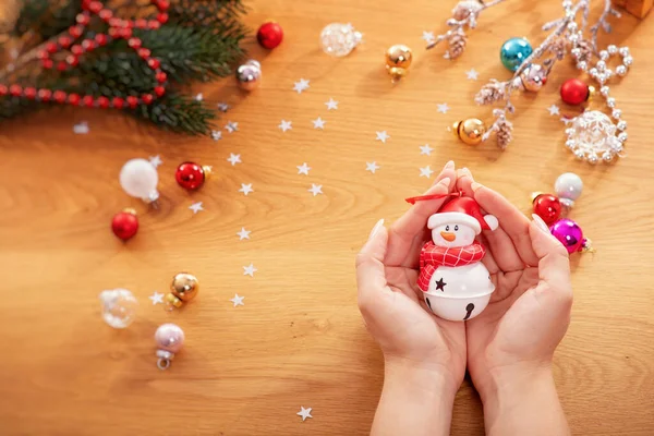 クリスマスのコンセプト 人間の手は 背景にお祝いの光とクリスマスの装飾品を持つ雪だるまの形でクリスマスの装飾を保持します — ストック写真