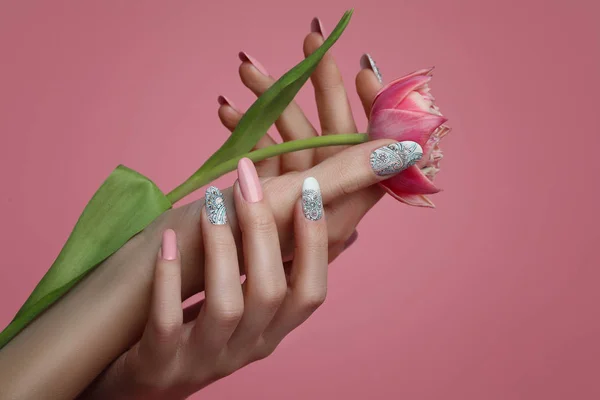 Sanat tasarım çivi. El ile pembe manikür pembe arka plan. Yakın kadar olan kadın el ile Trendy Pembe çivi ile bahar çiçek. 