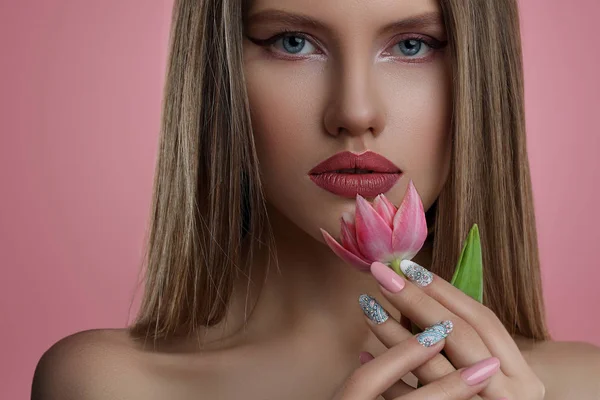年轻女子与花的美丽肖像 模型女孩与专业化妆和指甲艺术修指甲在粉红色的背景 — 图库照片