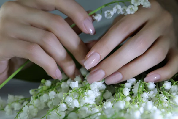 woman nails, manicure with flowers. Nails covered with nude nail polish.