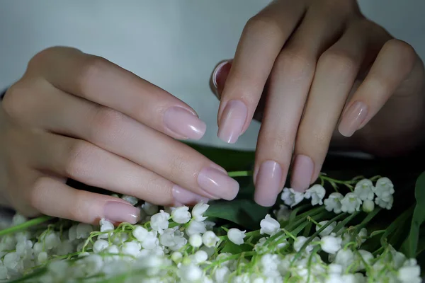 woman nails, manicure with flowers. Nails covered with nude nail polish.