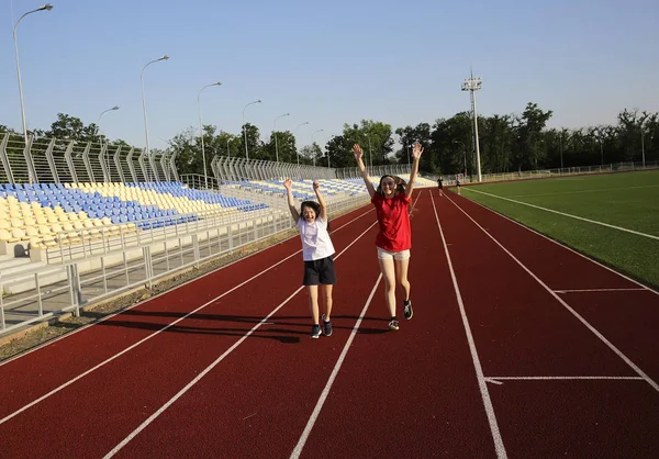 Little girl running on the stadium with a coach