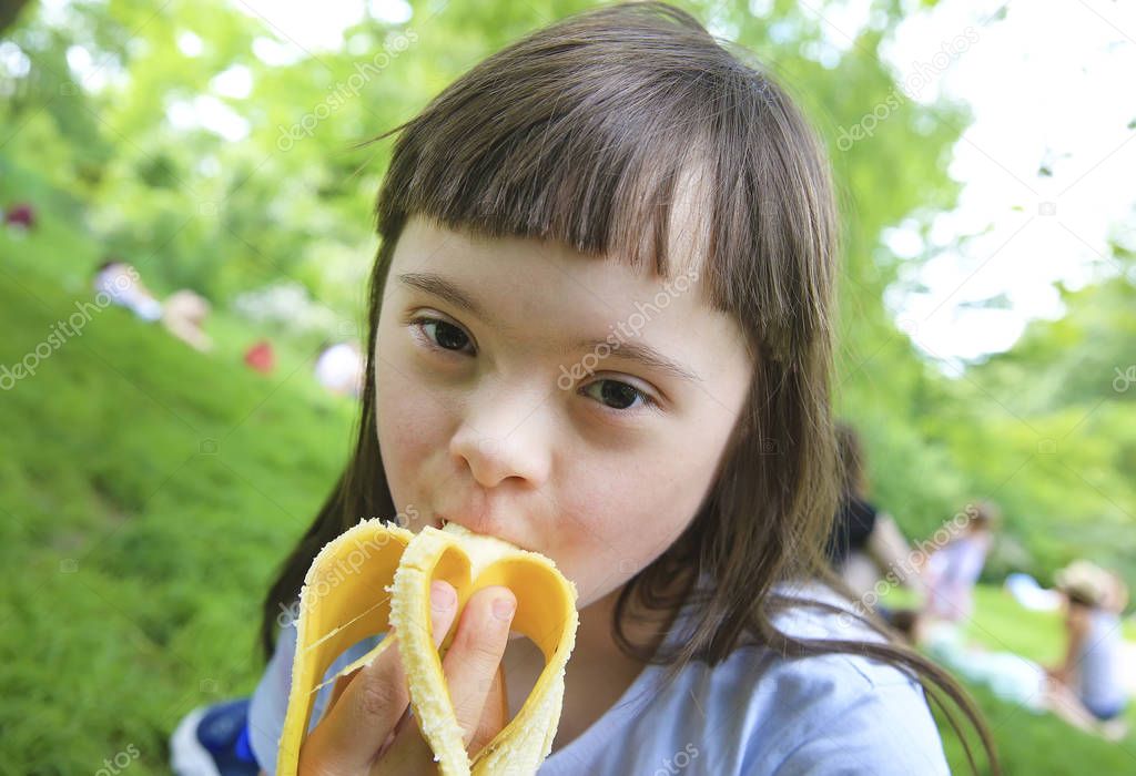 Young girl eating banana in the park
