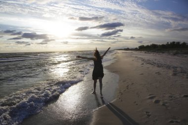 Günbatımı'nın deniz kıyısında kadın