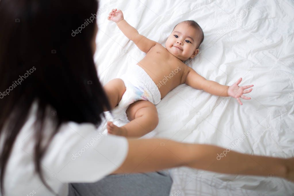 A asia mather playing with her daughter on the bed.