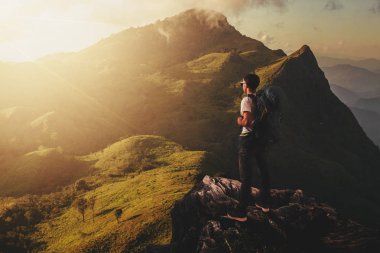 Sırt çantasıyla ve gün batımı sırasında uçurumların üzerinde tek başına duran gezgin vardır.