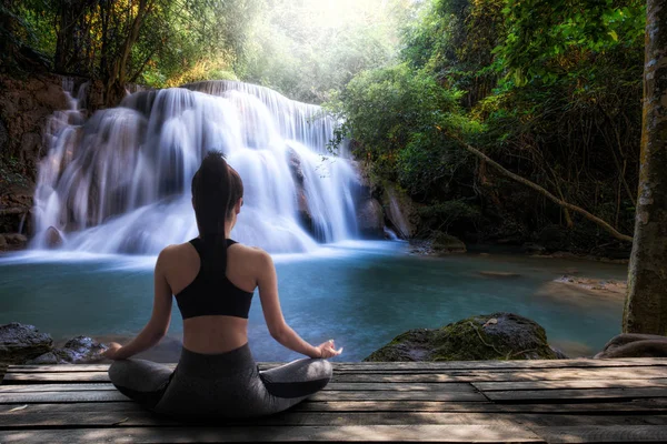 Pratik yoga nature.female mutluluk içinde genç bir kadın. Şelale arka plan.