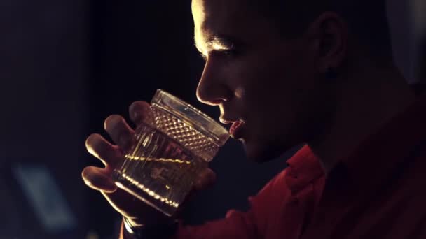 Un uomo con una camicia rossa sta bevendo whisky al bar. — Video Stock