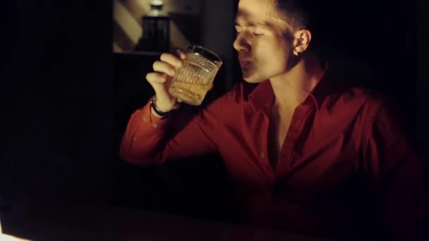 Man in een rood shirt is het drinken van whisky aan de bar — Stockvideo