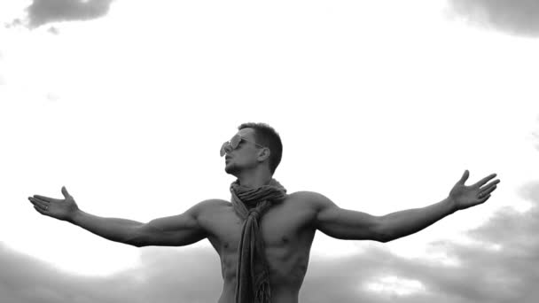 Mladý muž zvedá ruce na pozadí oblohy — Stock video