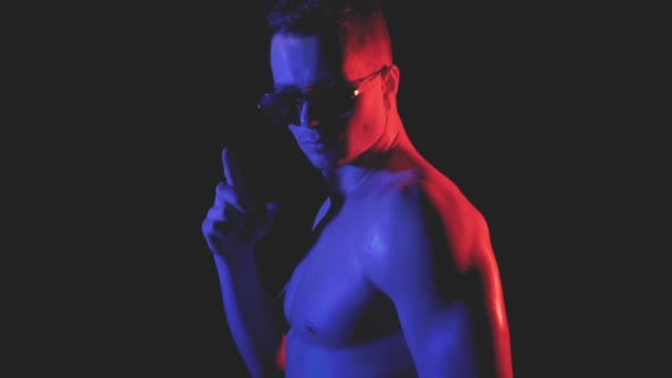 Young man with sunglasses in color light — Stock Video