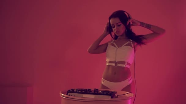 Sexy mujer DJ jugando en los tocadiscos en el fondo rosa — Vídeos de Stock