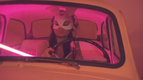 Mujer sexy en máscara en coche rosa — Vídeo de stock