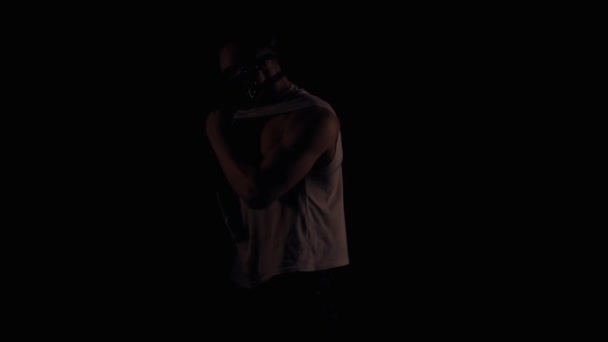 Maskeli adam yanıp sönen bir ışık altında poz — Stok video