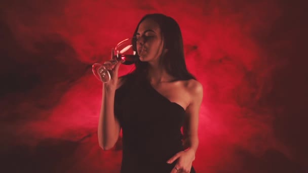 Mulher com um copo de vinho tinto em fumaça vermelha — Vídeo de Stock